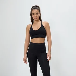 Žena pózuje ve sportovní podprsence a legínách černé barvy.