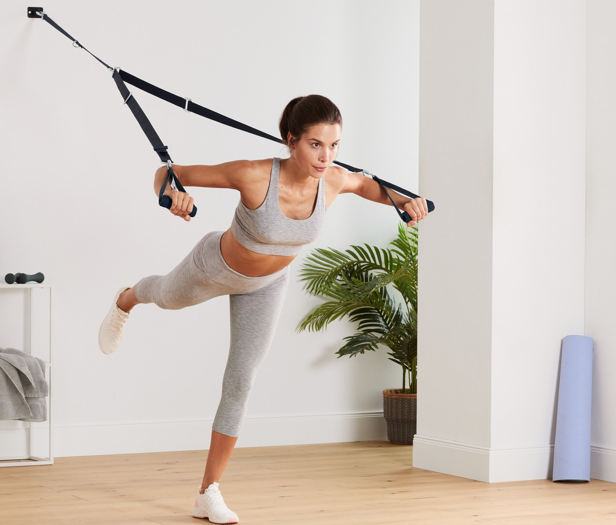 Žena cvičí s závěsným posilovacím systémem.