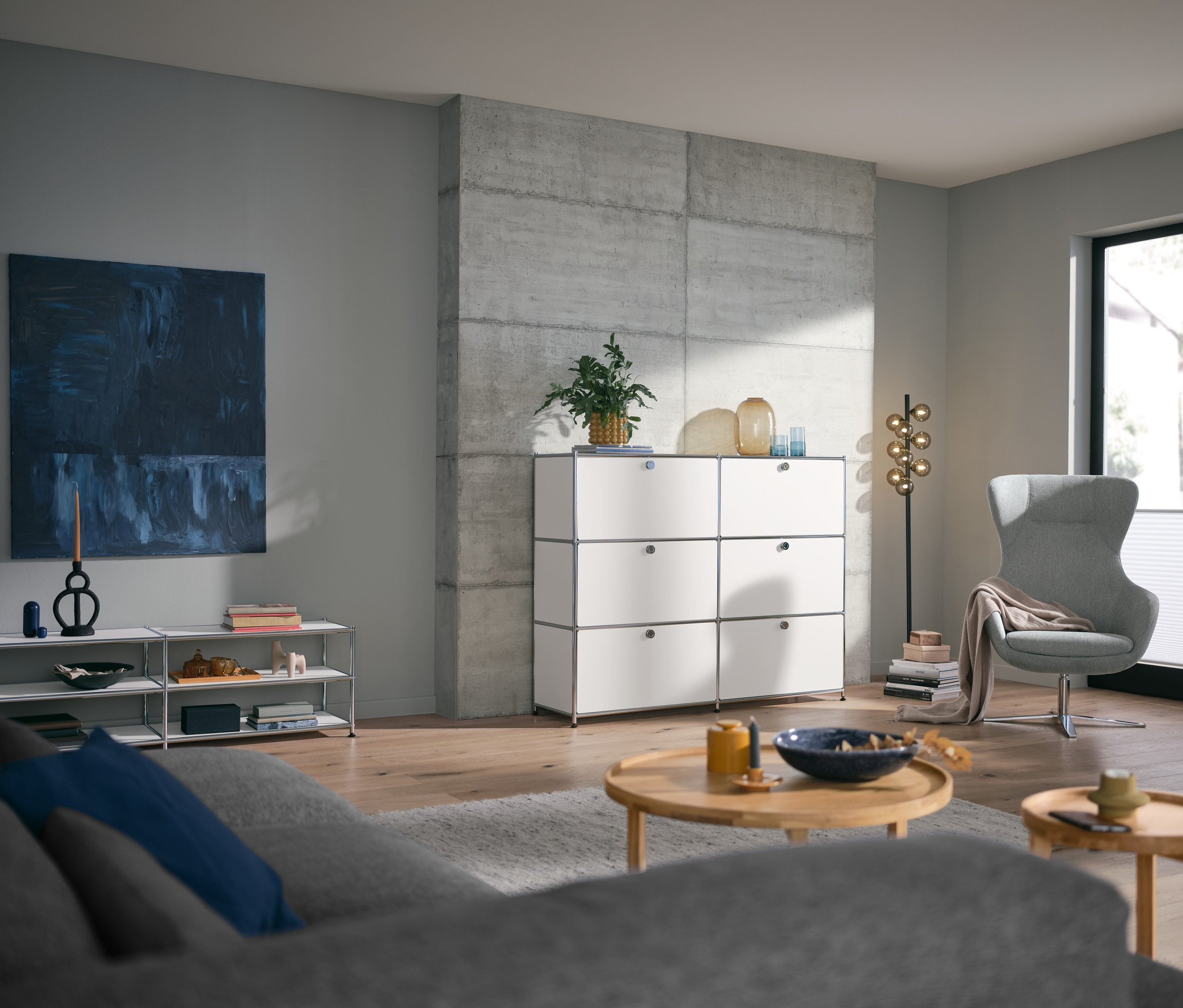 Obývací pokoj s kulatým konferenčním stolkem a bílou kovovou komodou CN3 se 6 výklopnými dvířky.