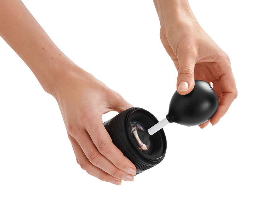 Žena čistí objektiv fotoaparátu pomocí Štěteček s balonkem na čištění proudem vzduchu.