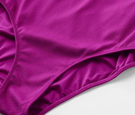 Detail fialových plavek se strukturovaným povrchem.