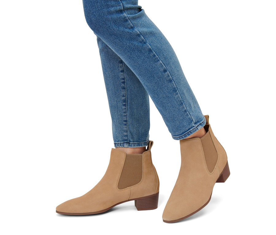 Nohy v modrých džínách a kotníkových botách z velurové kůže.