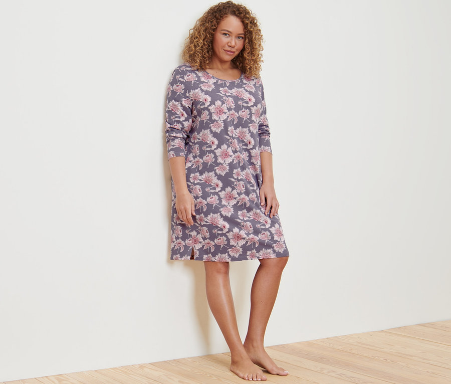 Žena pózuje v noční košili s květinovým vzorem.