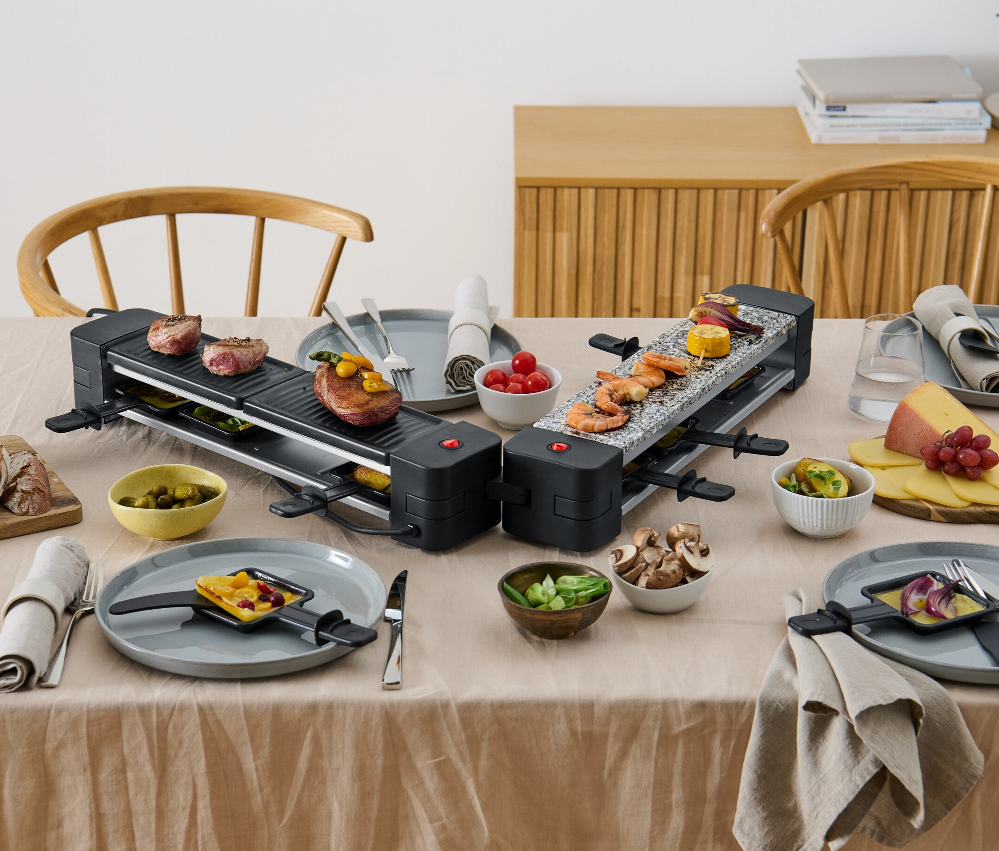 Dva skládací raclette grily s jídlem na stole.