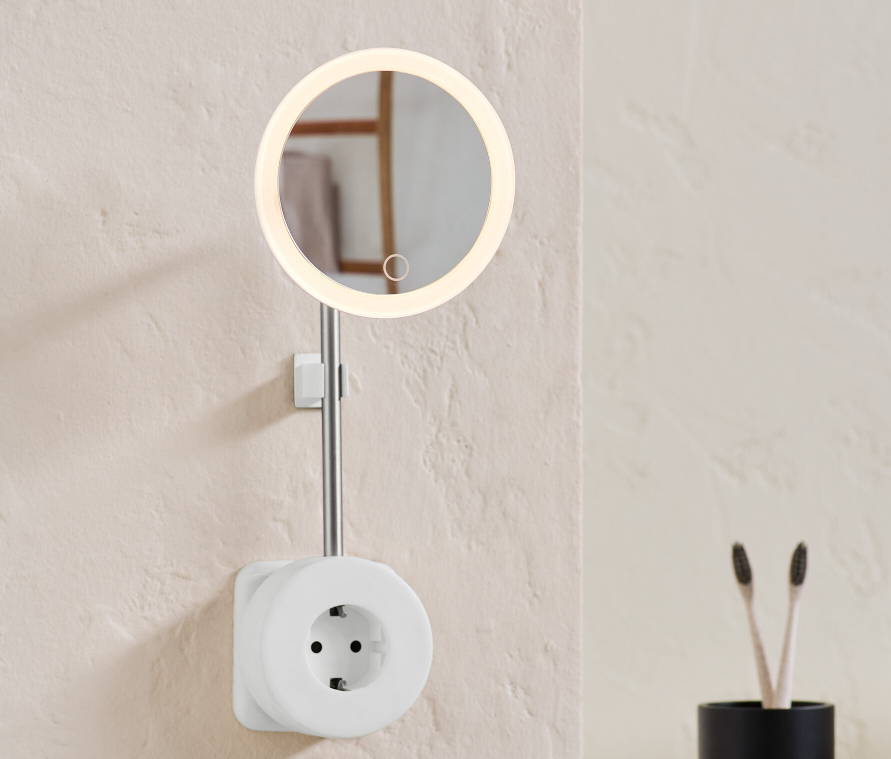 Na zdi je zásuvka s LED kosmetickým zrcátkem.