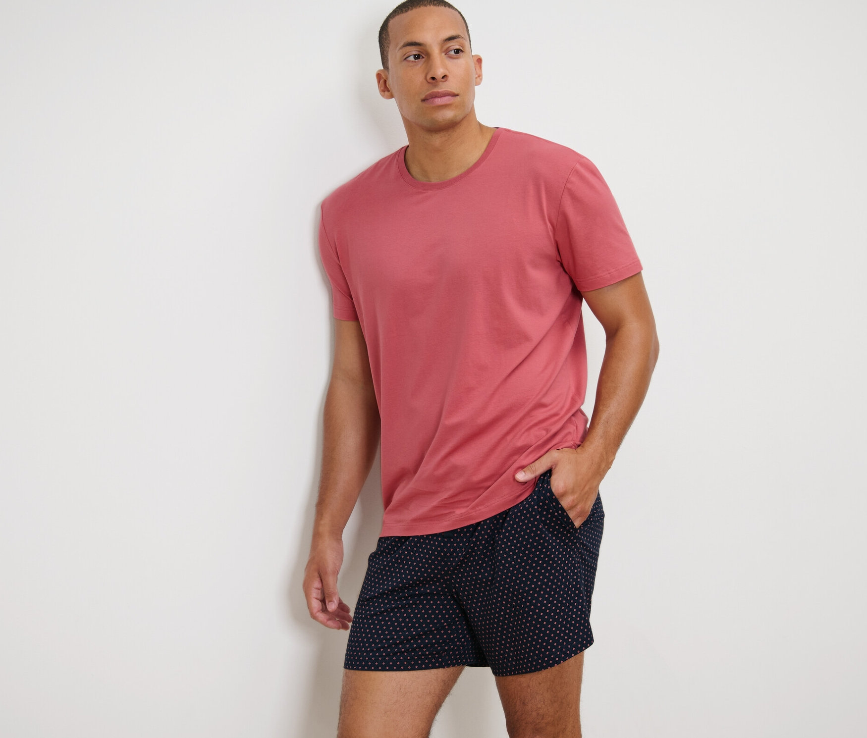 Muž opřený o zeď má na sobě krátké pyžamo s modalem.