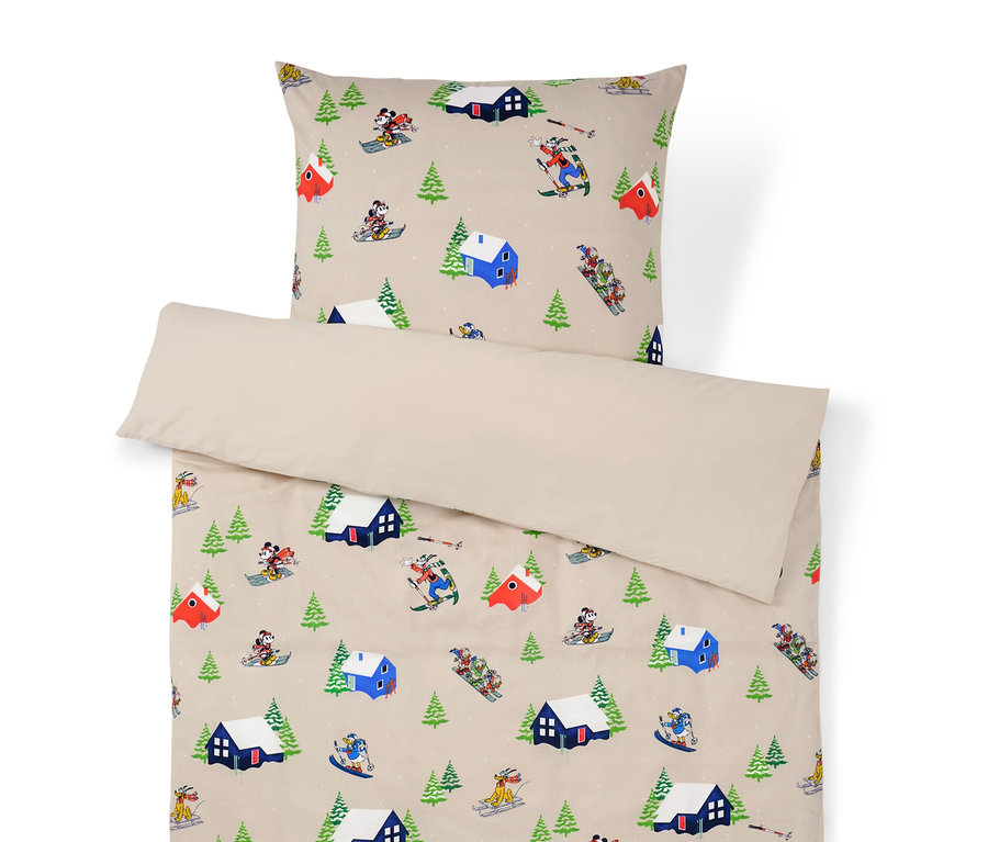 Ložní souprava s potiskem zimní krajiny s domy, stromy a lyžaři.