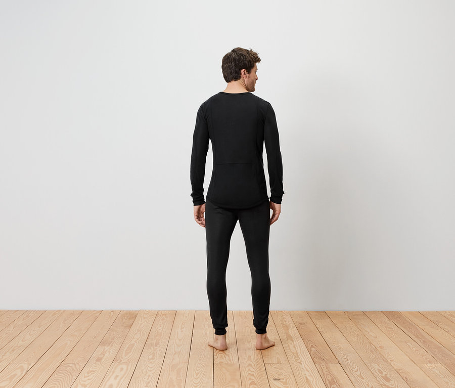 Muž stojí zády, oblečený v černém termoprádle.