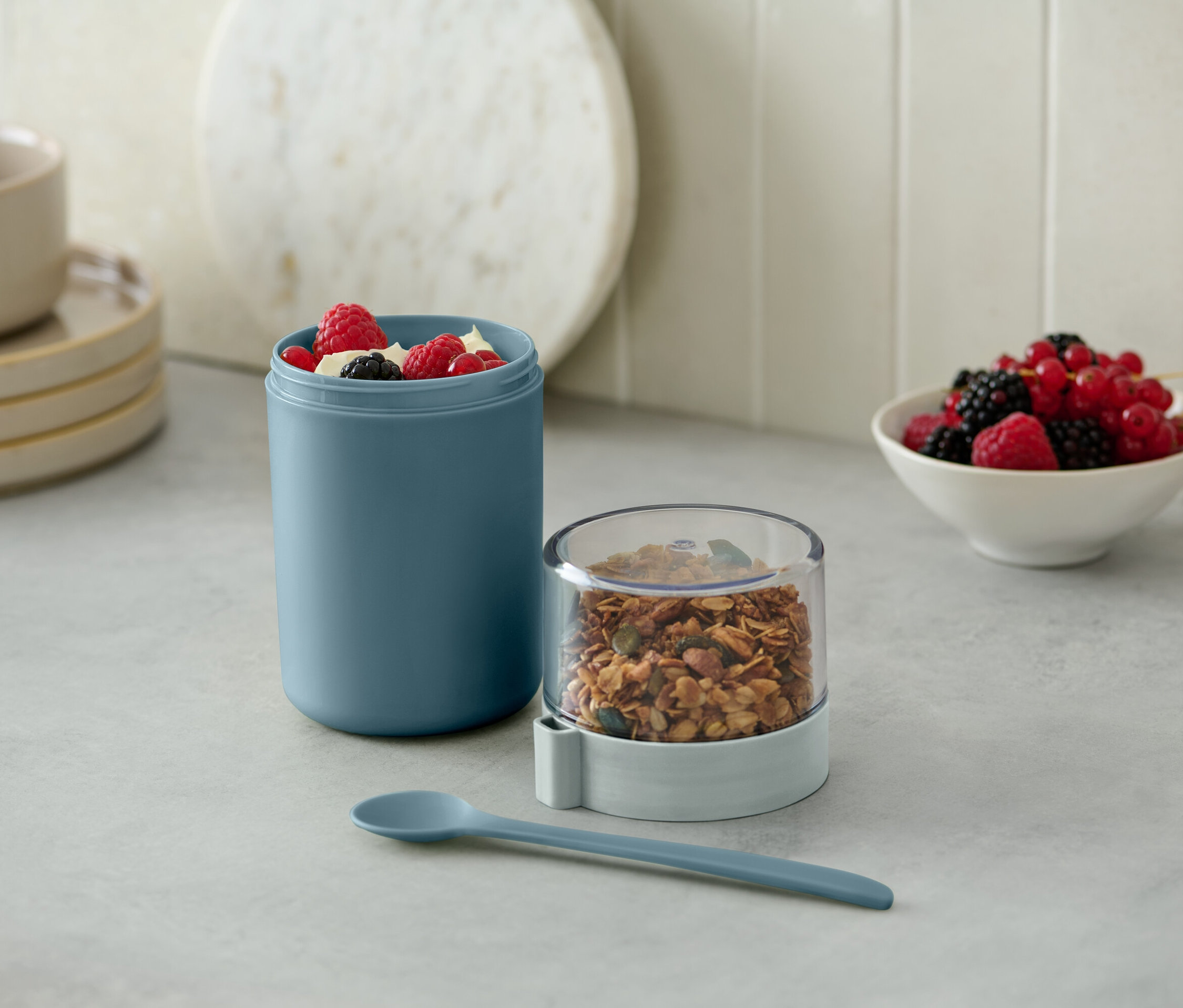 Zelený kelímek na jogurt na cesty s müsli a bobulemi.