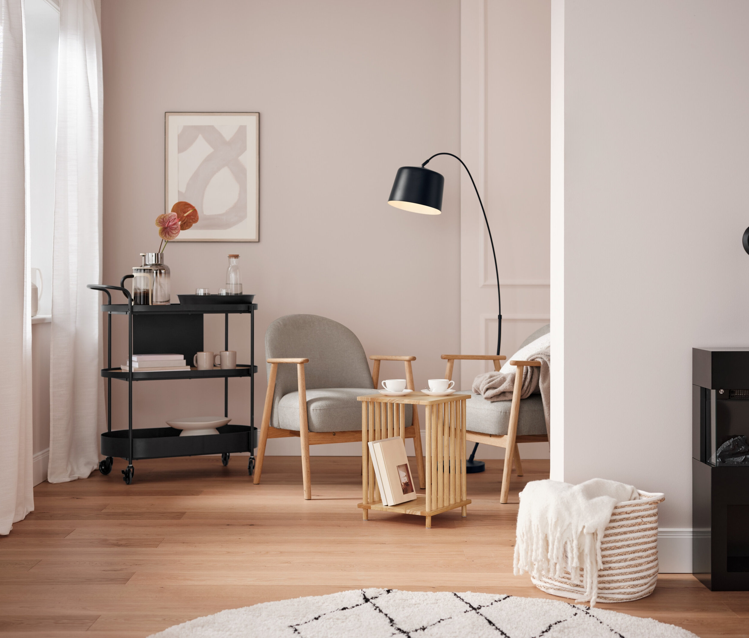 Obývací pokoj s černým servírovacím vozíkem, dvěma šedými křesly a černým krbem.