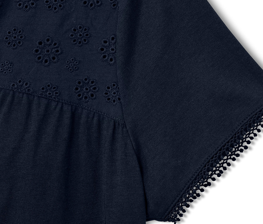 Detail tmavě modrého trička s výšivkou.