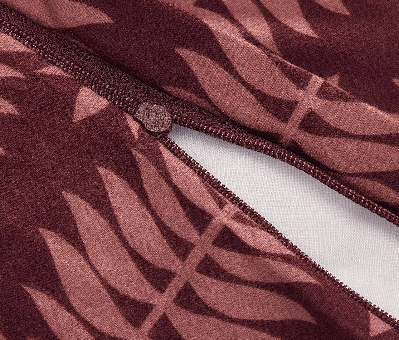 Detailní záběr na zip u zimního žerzejového povlečení s listovým vzorem.