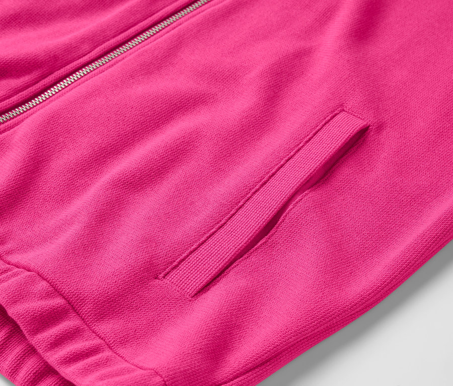 Detail růžové bundy se zipem a kapsou.