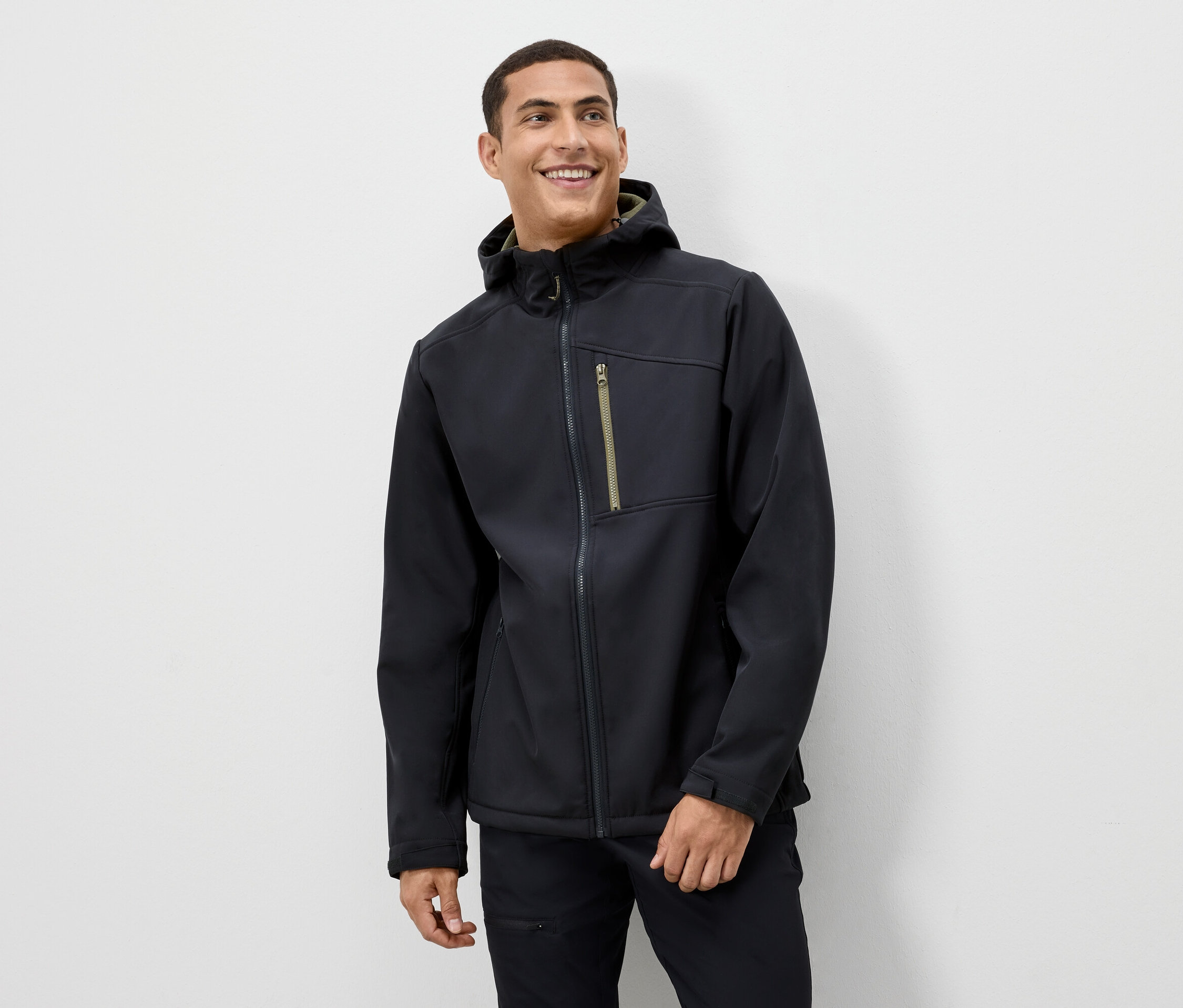 Muž se usmívá a má na sobě černou bundu s kapucí.