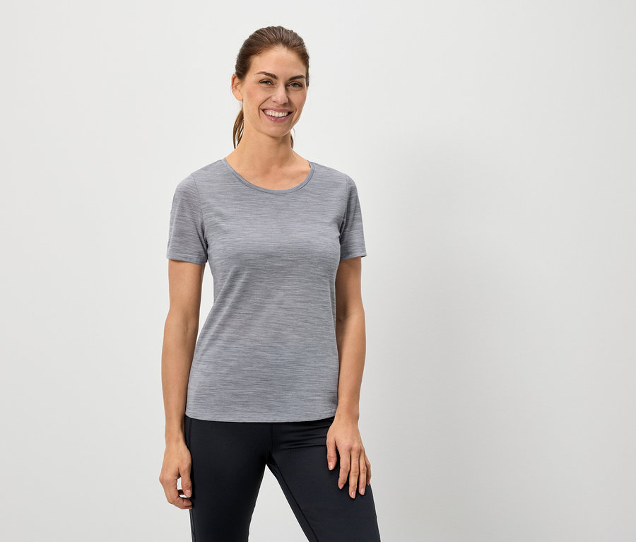 Žena má na sobě šedé tričko a černé legíny.
