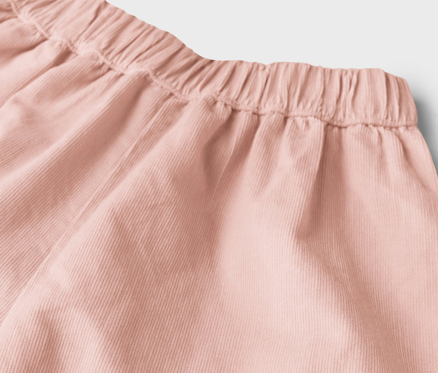Detailní záběr na růžové manšestrové šortky s elastickým pasem.