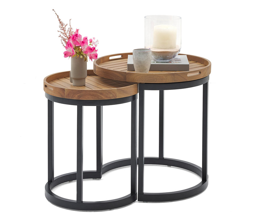 Dva kulaté odkládací stolky ze dřeva a kovu, jeden s vázou s růžovými květinami a druhý se svíčkou ve skleněné nádobě a šálkem.