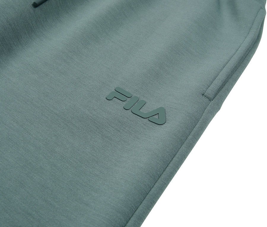 Detailní záběr na tyrkysové tepláky Fila se stahovací šňůrkou.