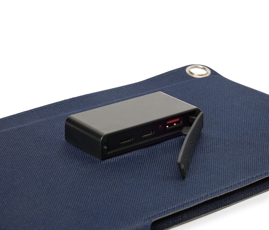 Černá baterie leží na modrém povrchu látky, s viditelným USB portem.