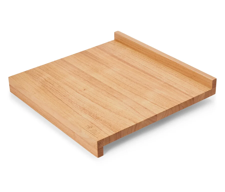 Obdélníkové světle hnědé dřevěné prkénko leží diagonálně na bílém povrchu.