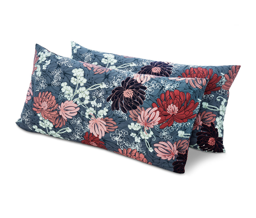 Dva obdélníkové polštáře s květinovým vzorem v odstínech šedé, růžové, červené a bílé leží na sobě na bílém pozadí.