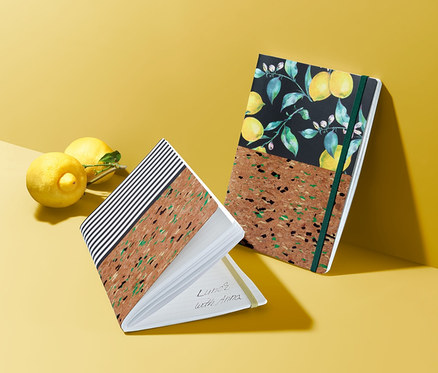 Dva korkové bloky leží na žlutém povrchu vedle dvou citronů.