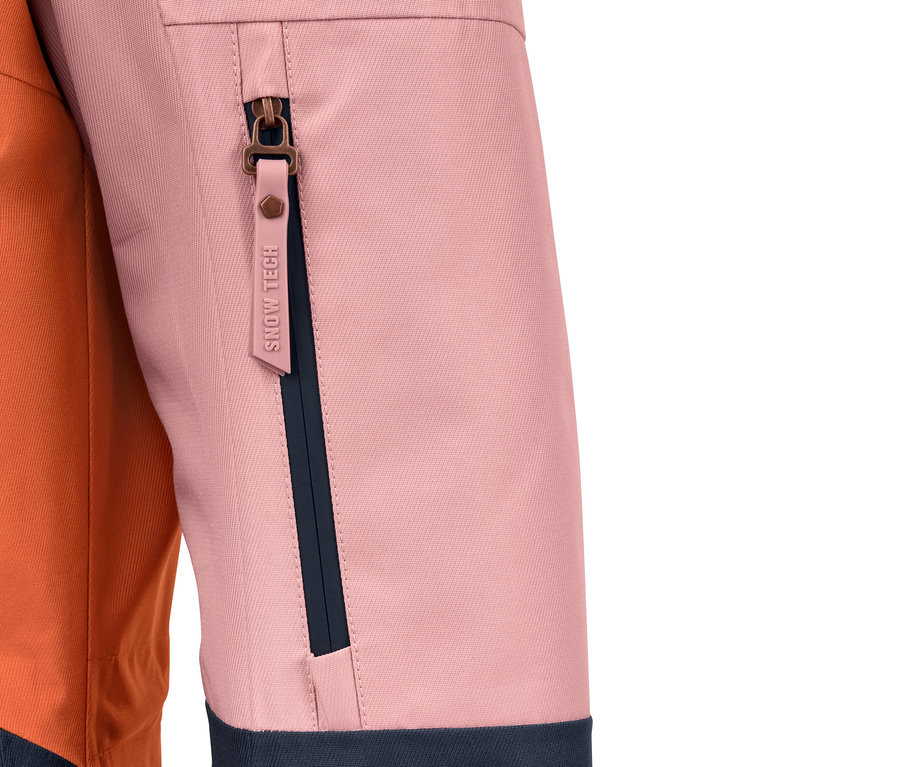 Detail barevně blokované lyžařské bundy s kapsou na zip.