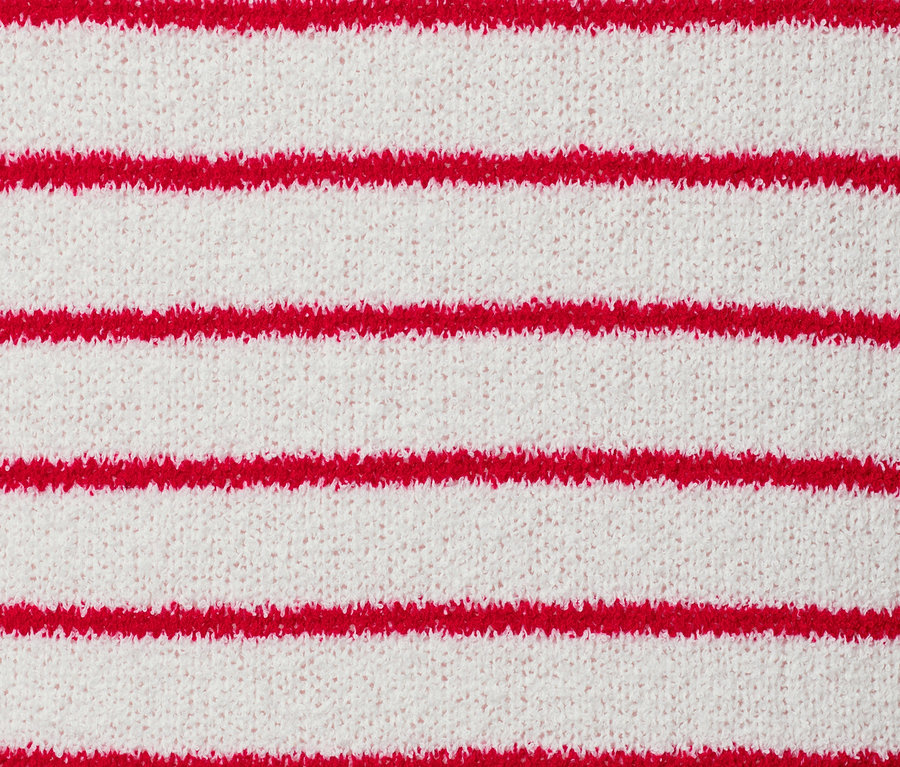 Detail pleteného kabátku v buklé stylu s červenými proužky.
