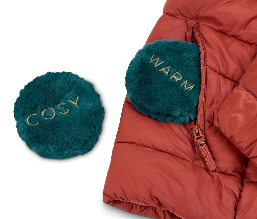 Červená péřová bunda s hřejivými polštářky do kapsy, 2 ks. Jeden polštářek je mimo bundu s nápisem "COSY" a druhý v kapse bundy s nápisem "WARM".