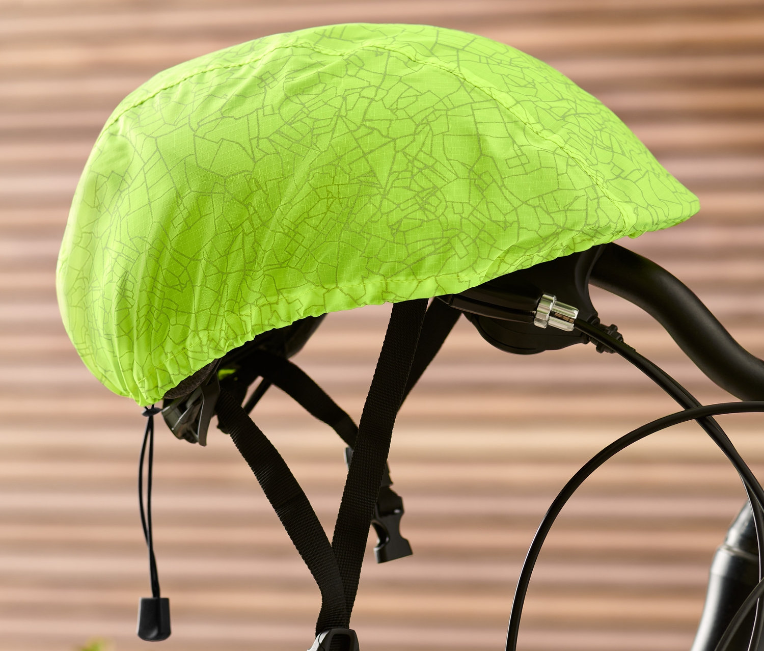 Na řidítkách kola je nasazený neonově žlutý potah na cyklistickou přilbu.