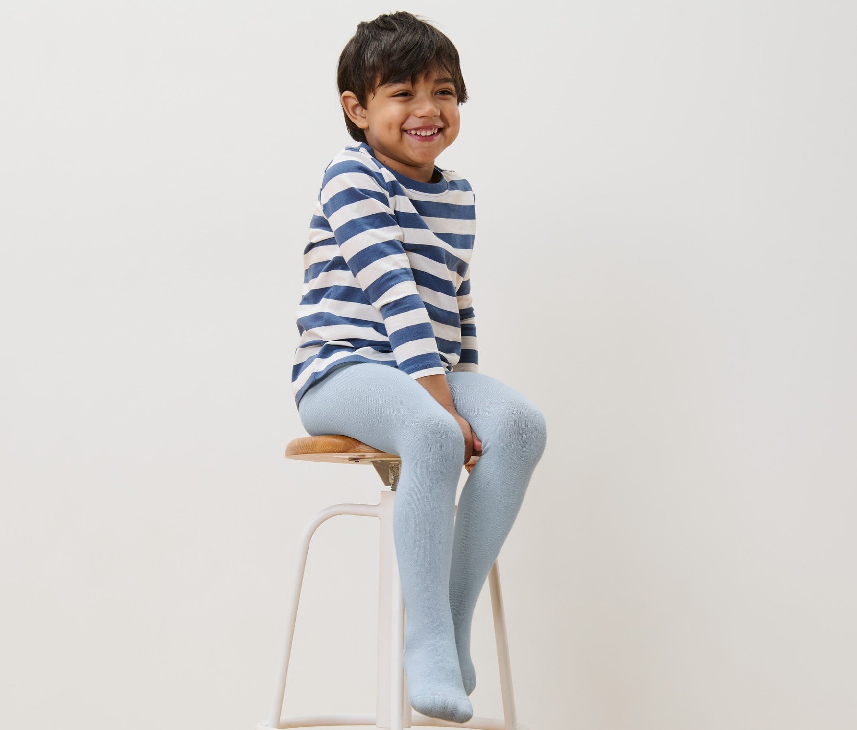 Chlapec sedí na stoličce a má na sobě modré bavlněné punčocháče.