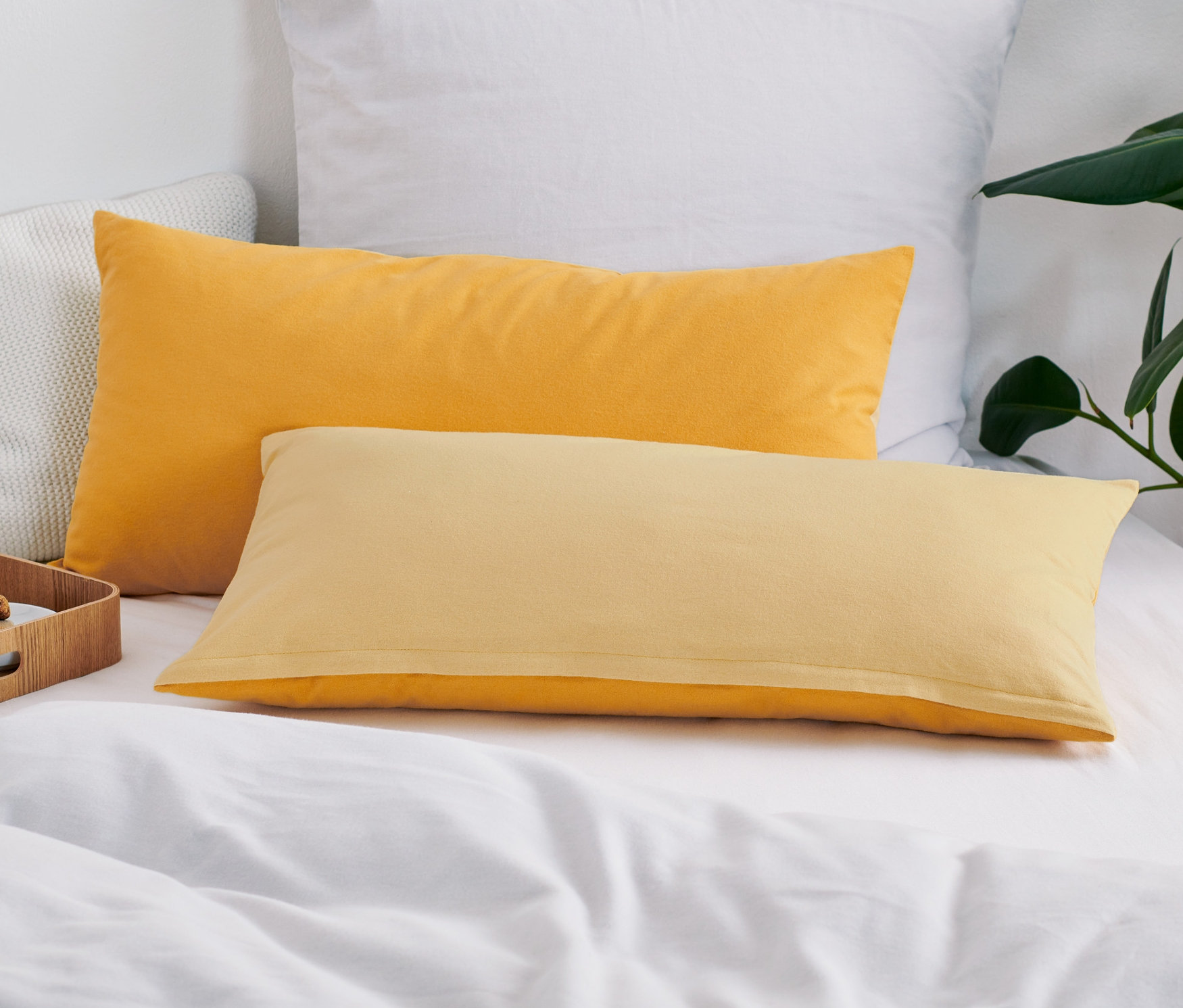 Na posteli leží dva žluté flanelové povlaky na polštáře.
