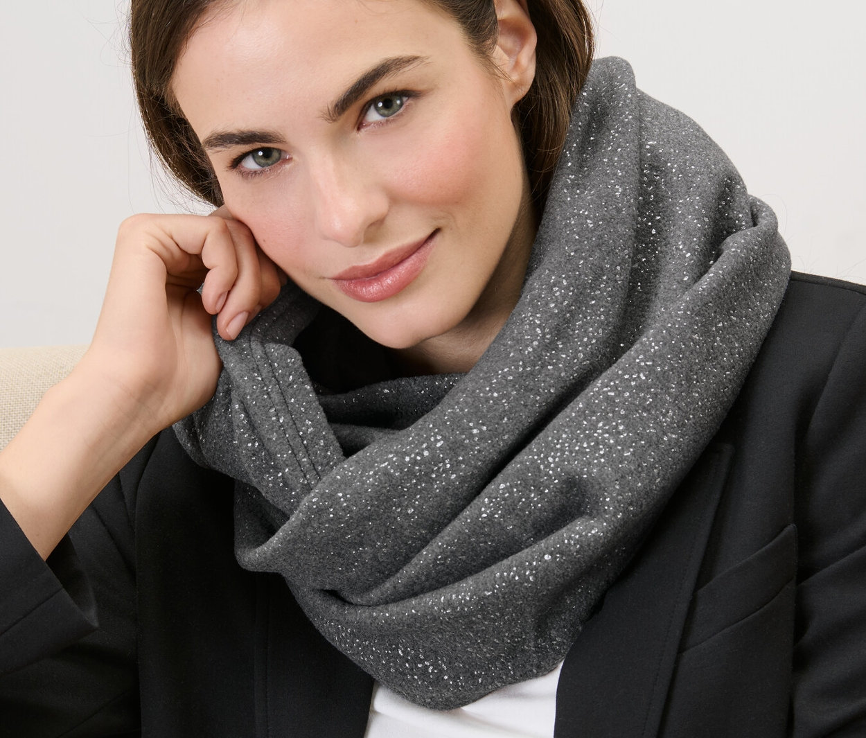 Žena sedí a má na sobě fleecovou kruhovou šálu se třpytivým efektem.
