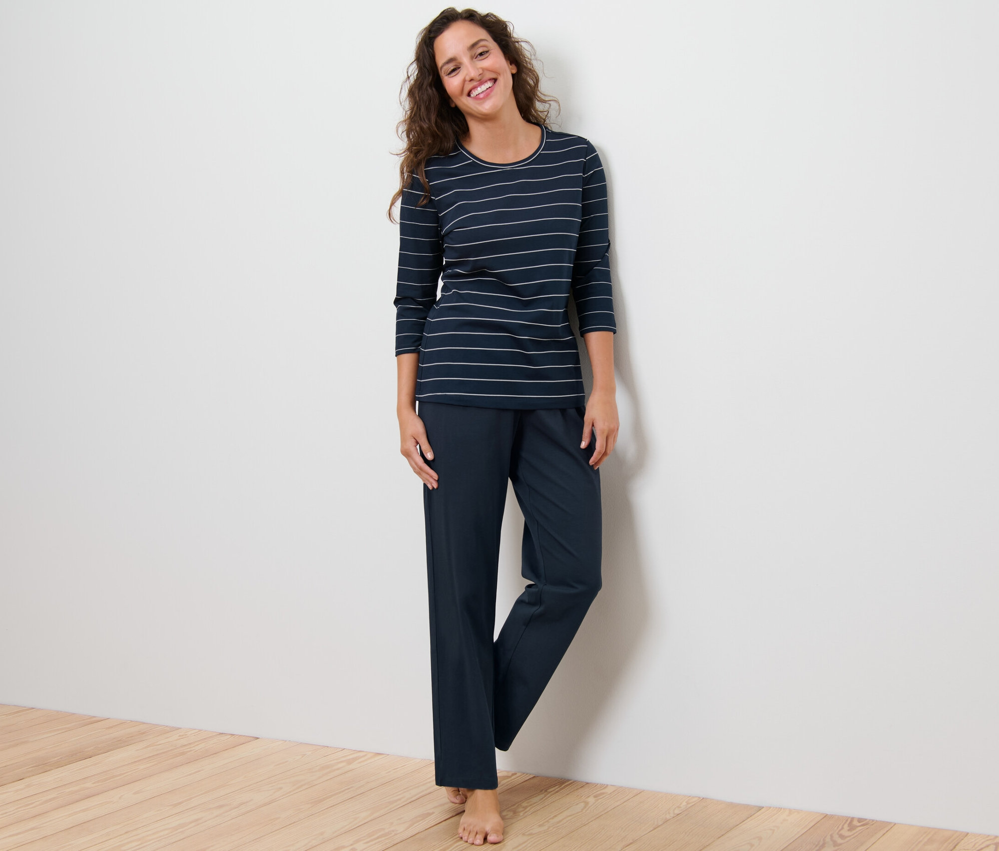 Žena stojí a má na sobě pyžamo s proužky.