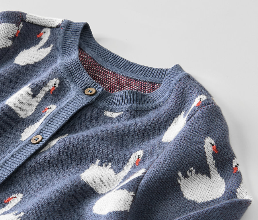 Detail modrého dětského pleteného svetru s labutěmi.