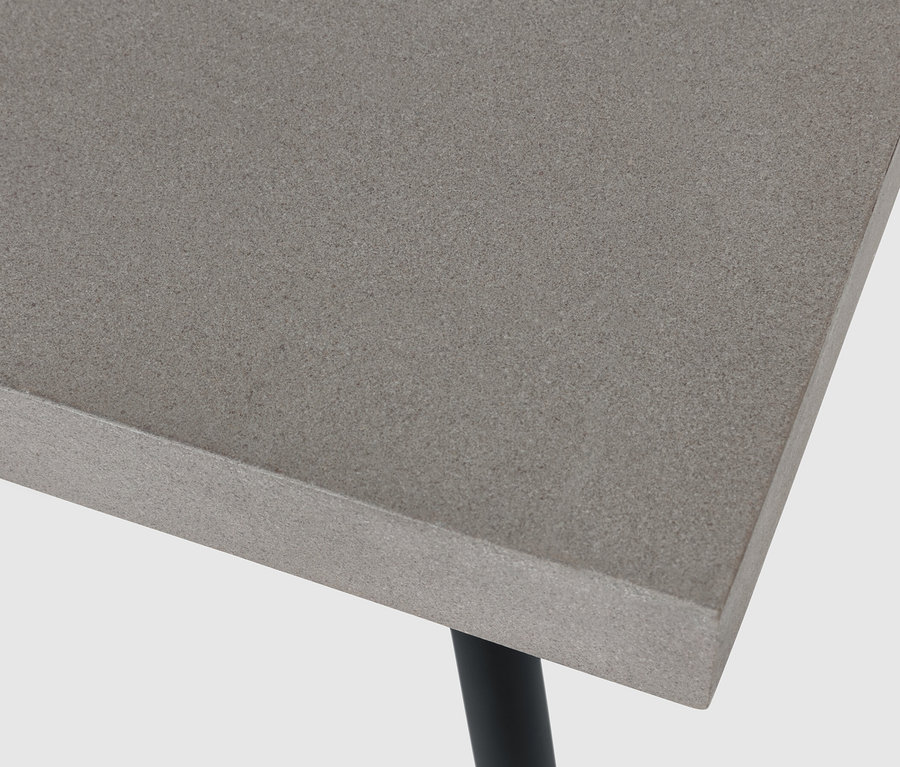 Detail konferenčního stolku s polycementovou deskou a černými nohami.
