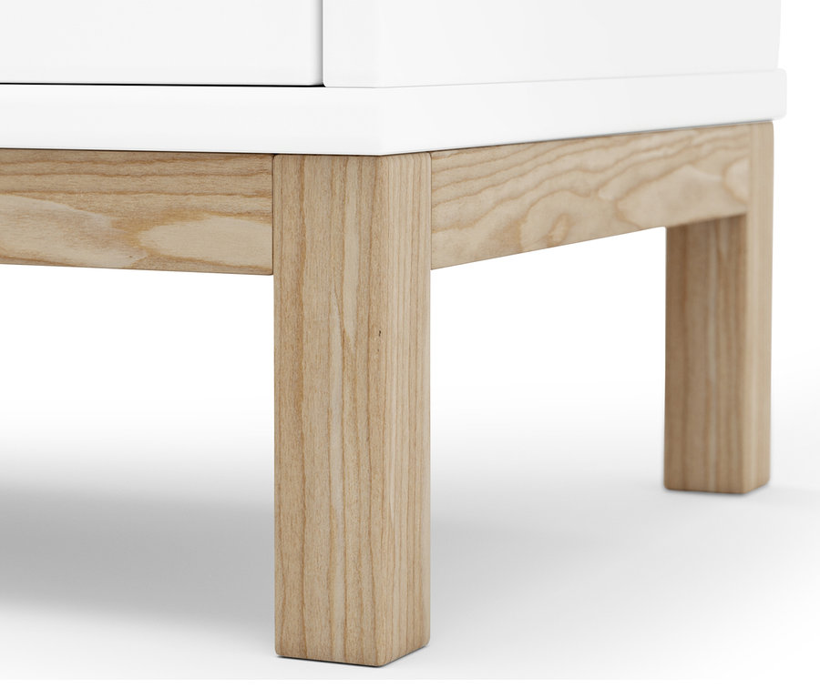 Detail spodní části bílého regálu s košem na prádlo s dřevěnýma nohama.