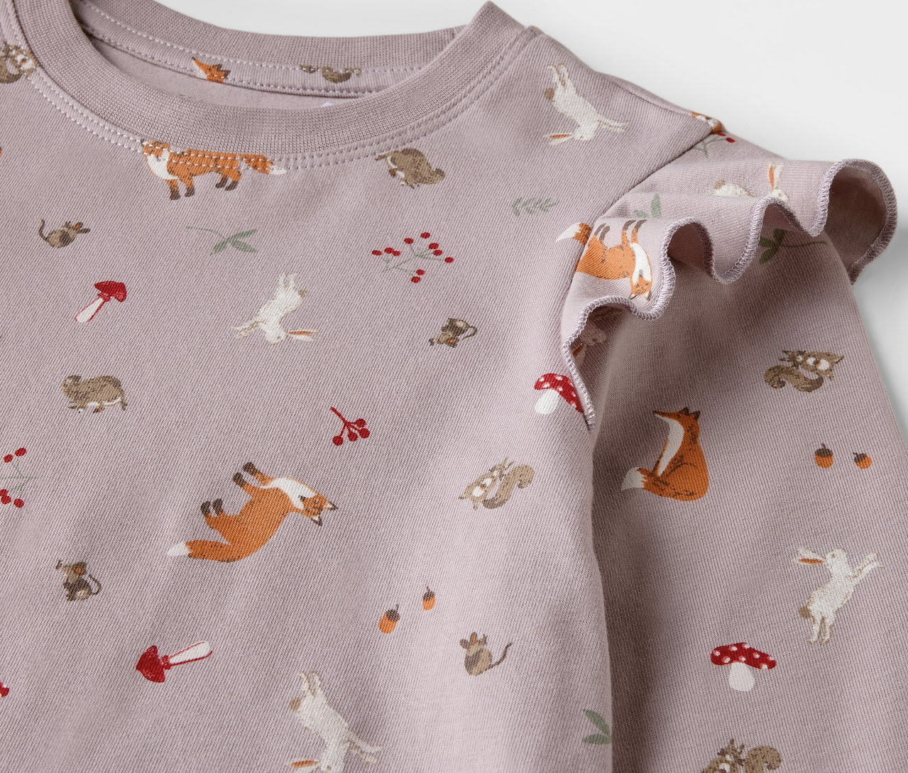 Detail dětské noční košile s potiskem lišek, zajíců, veverek a hub.