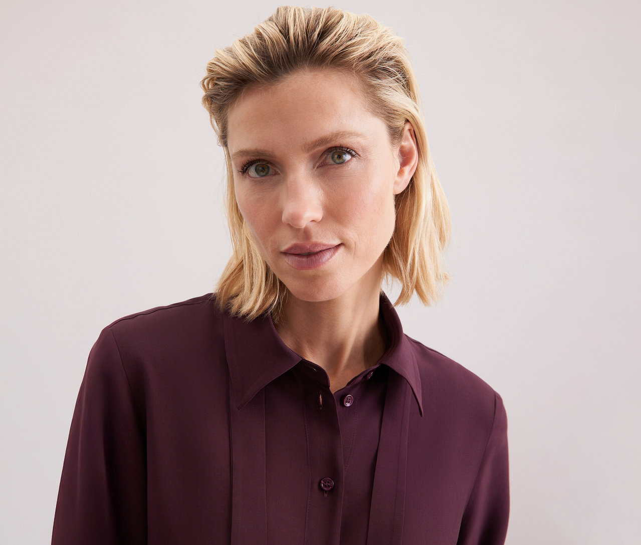 Žena má na sobě viskózovou halenku s vázačkou Seidensticker.