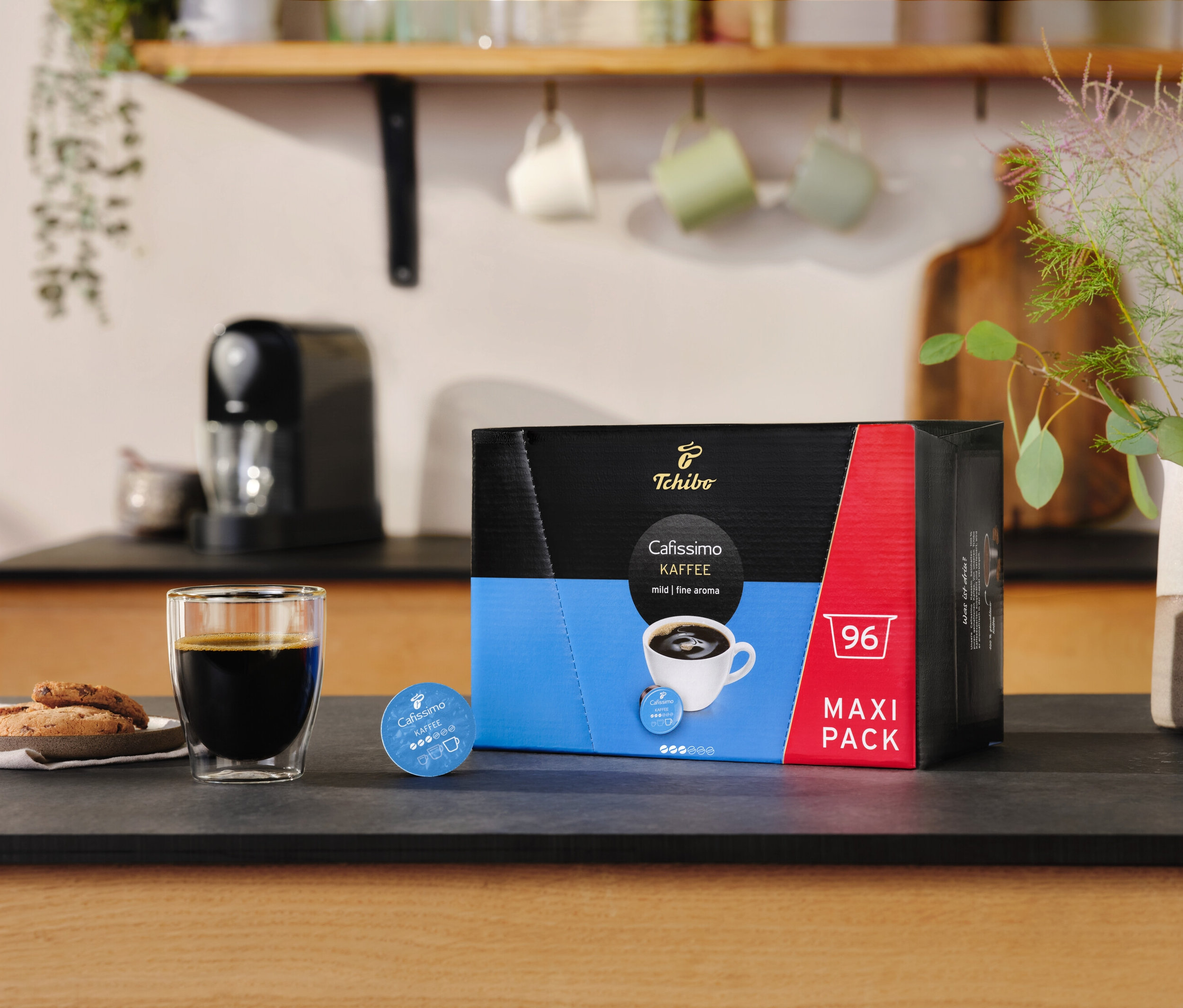 Sklenice kávy a sušenky vedle balení Cafissimo výrazná káva – 30 kapslí.
