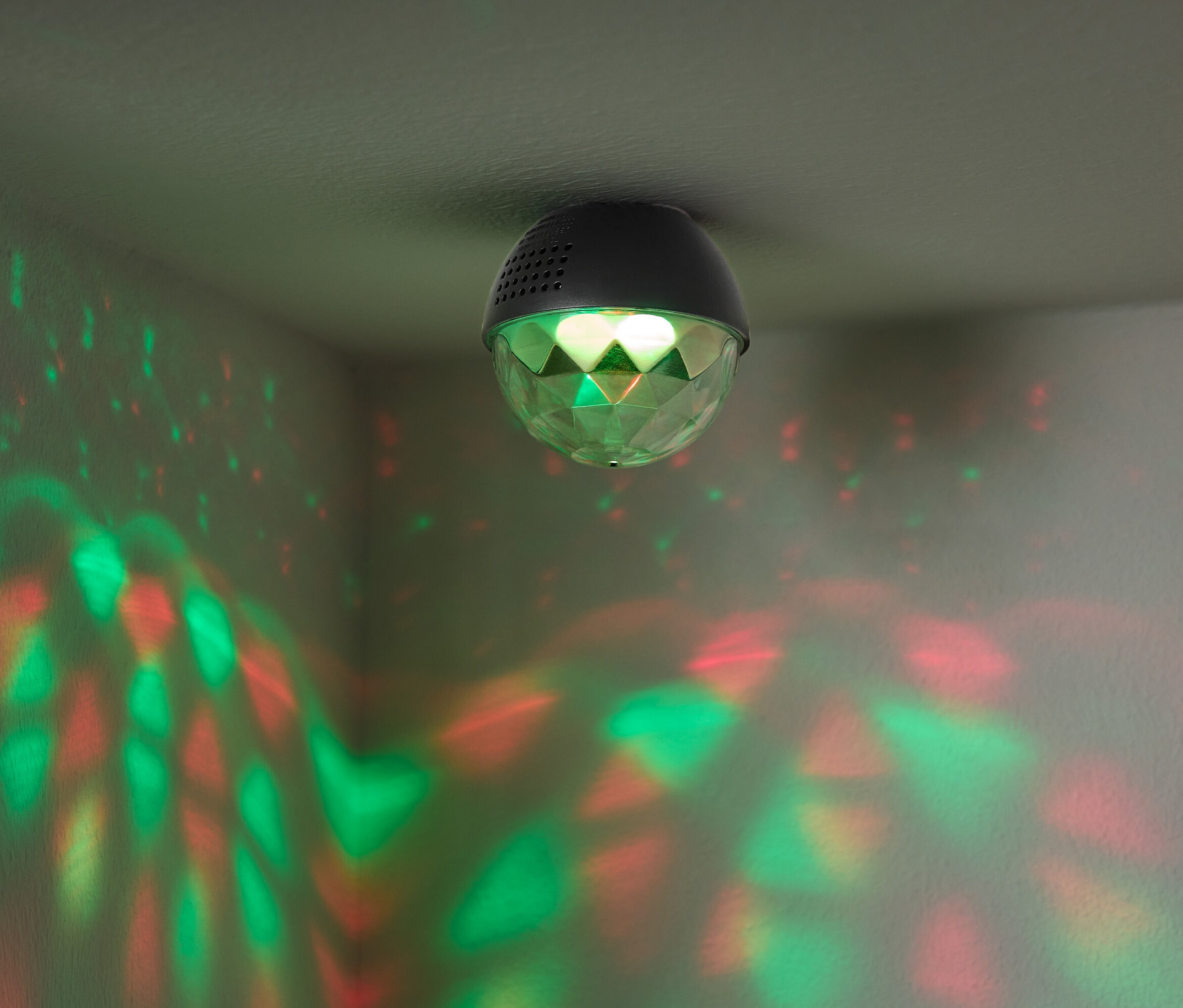 Disco koule připevněná ke stropu vrhá na stěny červené a zelené světlo.