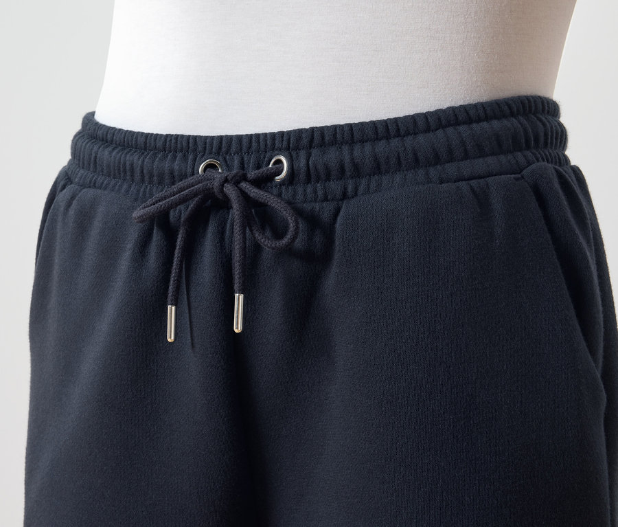 Detail tmavě modrých tepláků s tkaničkou v pase.