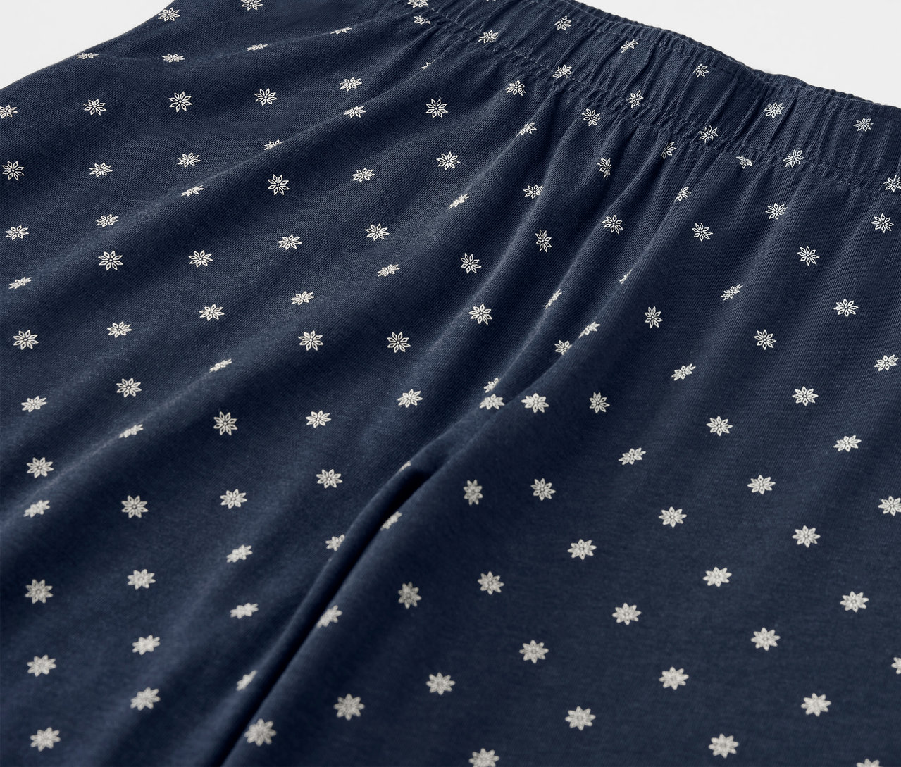 Detail tmavě modrých kalhot s bílými květy a elastickým pasem.