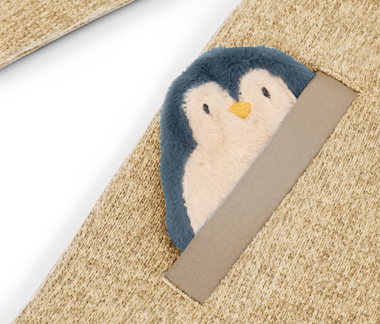 Detail béžového koberce s našitým plyšovým tučňákem.