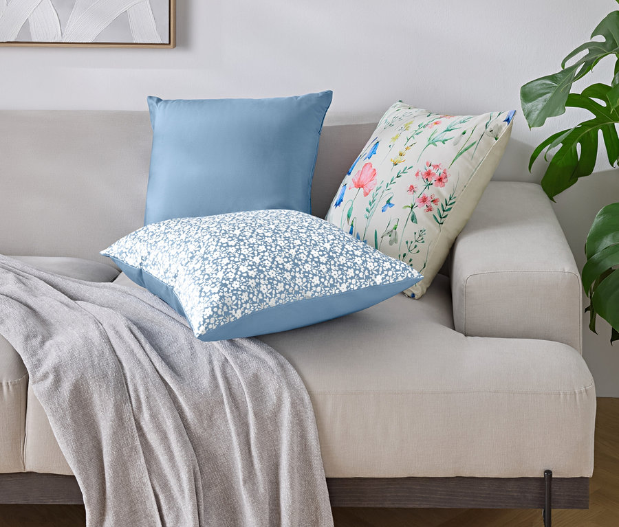 Na pohovce leží tři polštáře a deka.