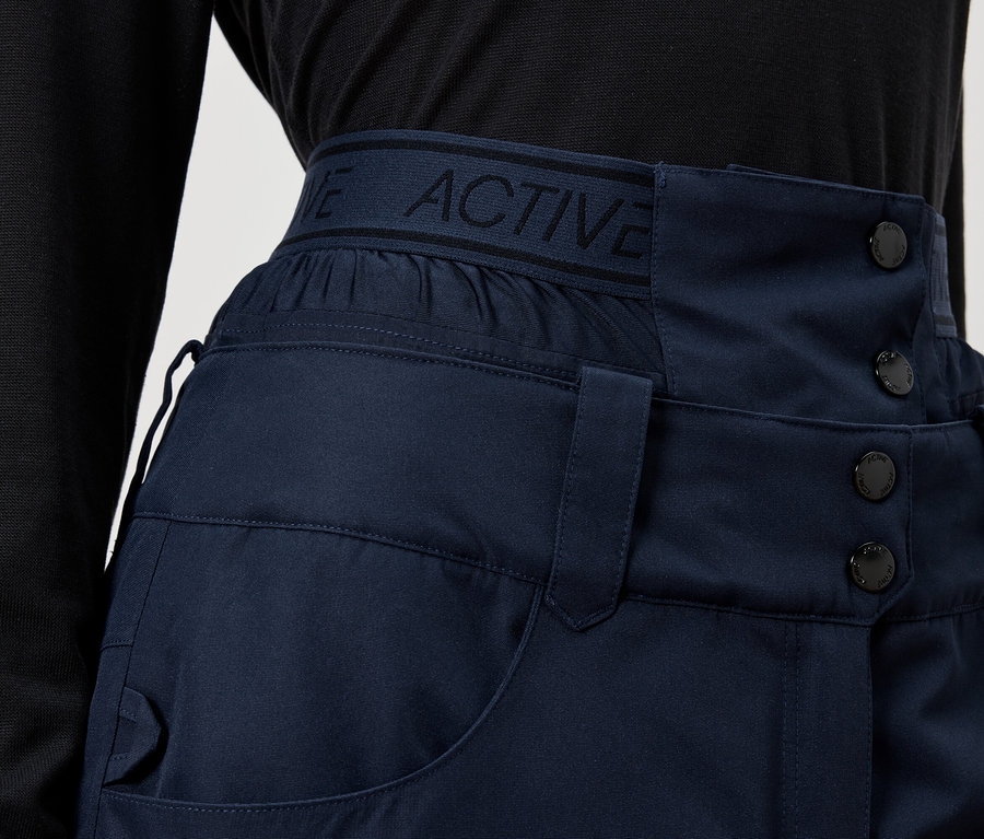 Detail modrých kalhot s vysokým pasem a knoflíky.