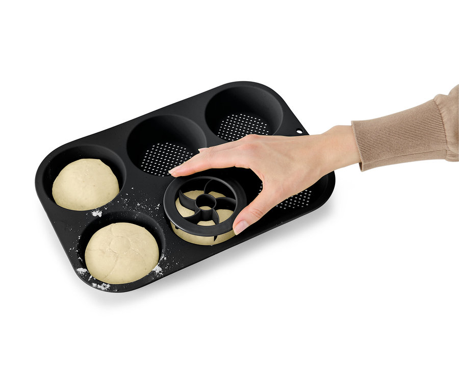 Ruka tlačí vykrajovátko do těsta v černé formě na muffiny.