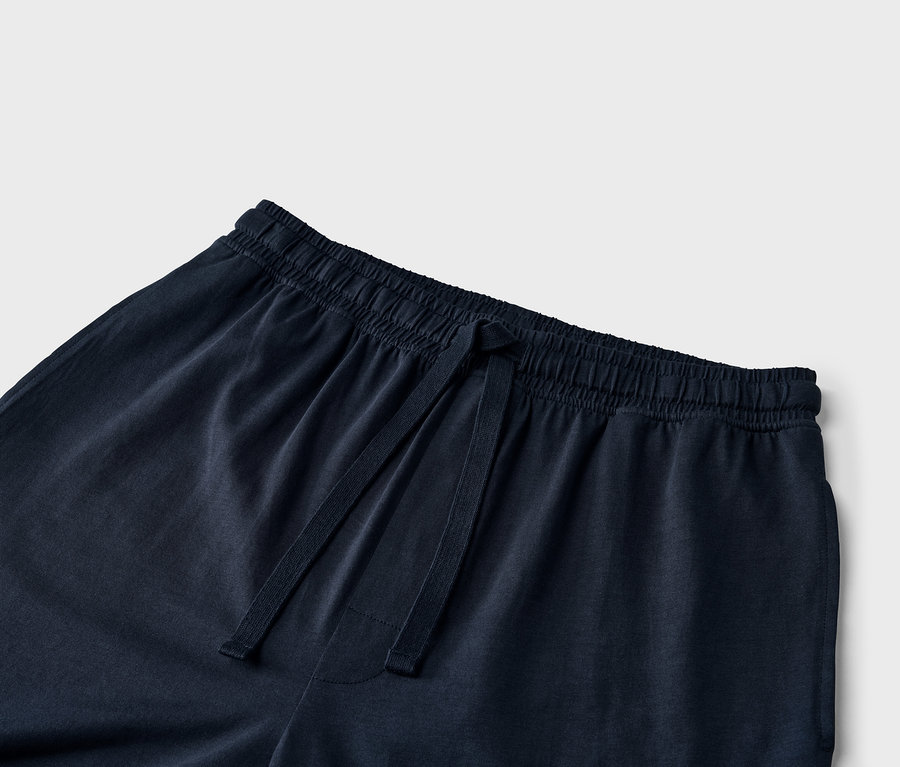 Detail modrých tepláků se stahovací šňůrkou v pase.