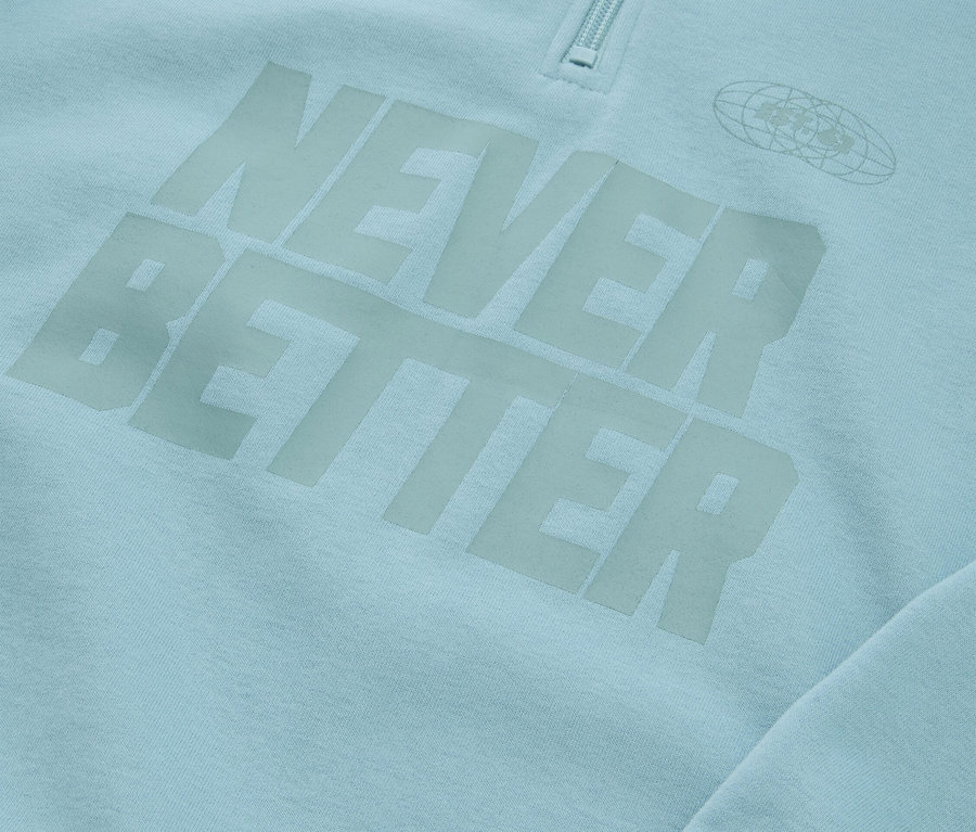 Detail světle modré mikiny s nápisem "NEVER BETTER" a zipem u krku.