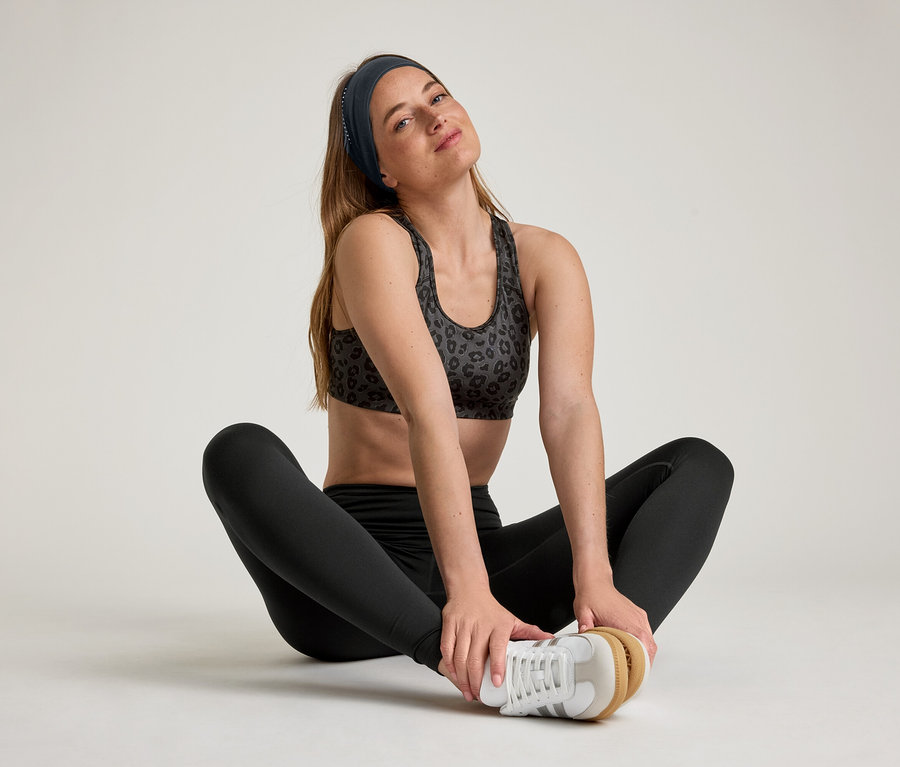 Žena sedí s roztaženýma nohama a má na sobě sportovní legíny »ActiveSoft«.